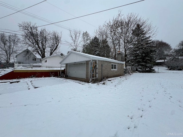 view of snowy exterior with an outbuilding and a garage