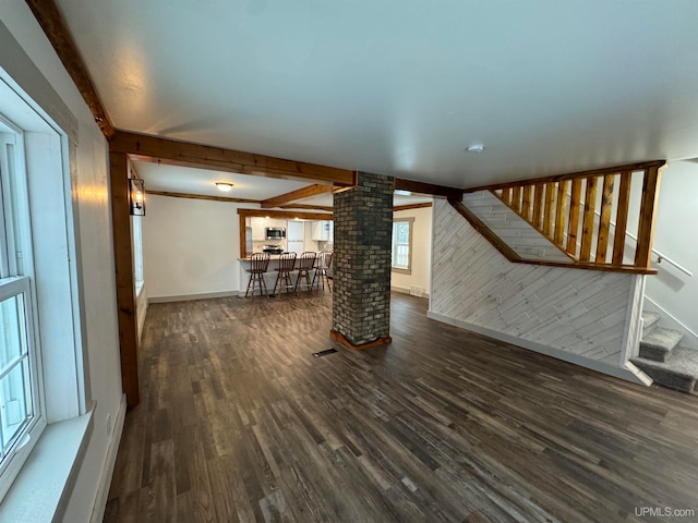 unfurnished living room featuring beamed ceiling, dark hardwood / wood-style flooring, and decorative columns