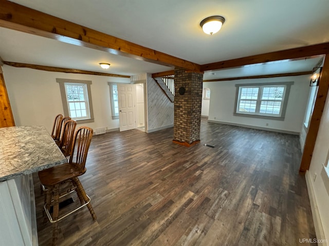 dining area featuring beamed ceiling, dark hardwood / wood-style floors, a wealth of natural light, and decorative columns