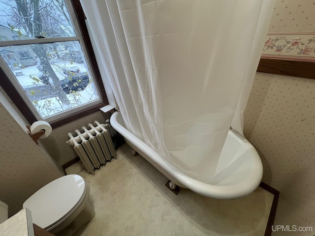 bathroom with radiator heating unit, toilet, and plenty of natural light