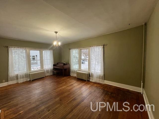 empty room featuring a wealth of natural light, dark hardwood / wood-style floors, and radiator