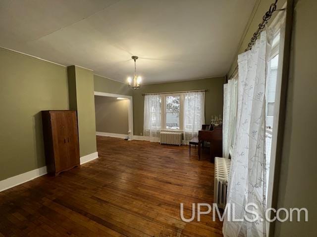 interior space with dark hardwood / wood-style flooring, radiator, and a notable chandelier