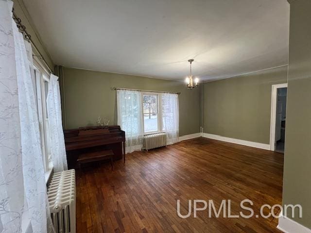 interior space featuring dark hardwood / wood-style floors, radiator heating unit, and a chandelier