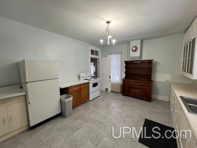 kitchen with radiator, white appliances, sink, pendant lighting, and a chandelier