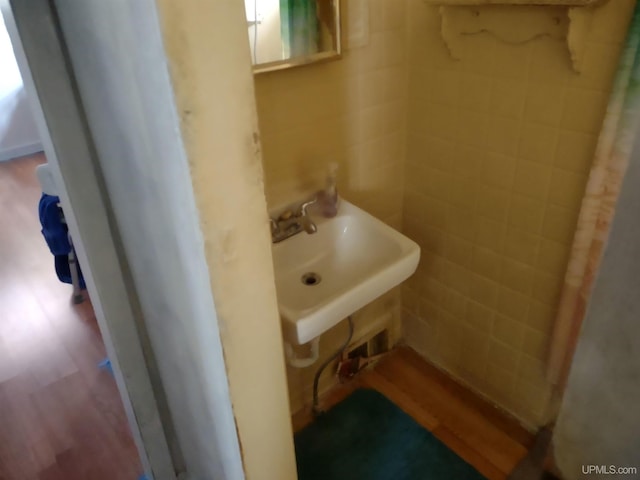 bathroom with hardwood / wood-style flooring, sink, and tile walls