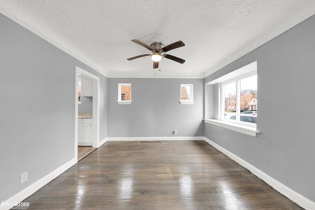 empty room featuring a textured ceiling, dark hardwood / wood-style floors, ceiling fan, and ornamental molding