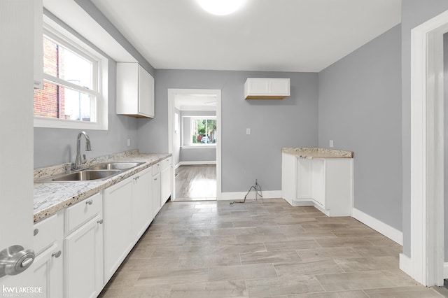 kitchen with white cabinetry, sink, and light hardwood / wood-style flooring