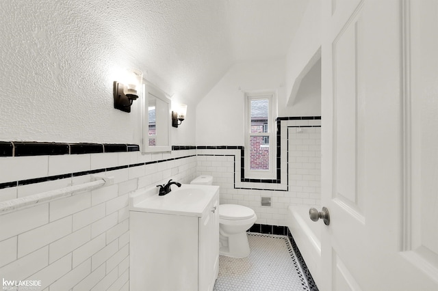 bathroom featuring tile patterned floors, vanity, a textured ceiling, tile walls, and lofted ceiling