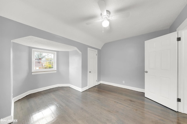 additional living space featuring lofted ceiling, ceiling fan, dark hardwood / wood-style flooring, and a textured ceiling