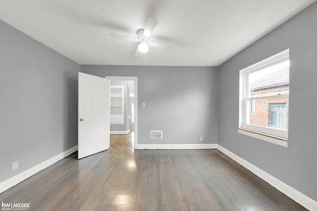 empty room featuring a textured ceiling, ceiling fan, and dark wood-type flooring