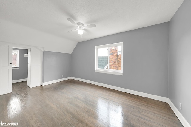 additional living space with a textured ceiling, ceiling fan, lofted ceiling, and dark wood-type flooring