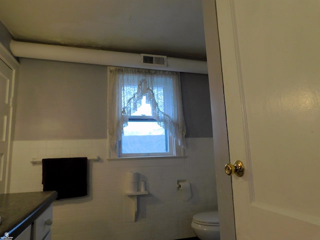 bathroom with vanity, toilet, and tile walls