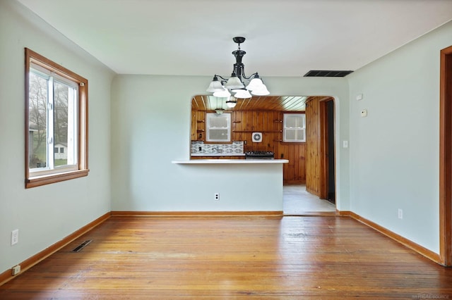 310 S Main St, Vassar, MI 48768 - kitchen with a chandelier, arched walkways, light wood finished floors, a peninsula, and baseboards
