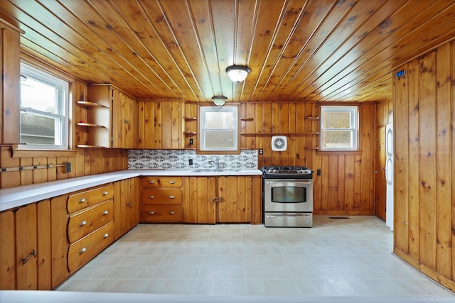 kitchen featuring sink, wooden ceiling, wooden walls, decorative backsplash, and stainless steel range with gas stovetop