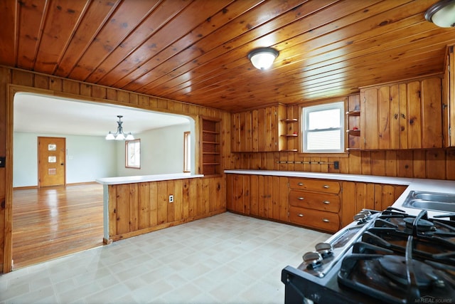310 S Main St, Vassar, MI 48768 - kitchen featuring brown cabinets, wood walls, open shelves, a peninsula, and a chandelier