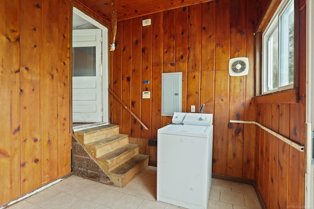 washroom featuring wooden walls, washer / dryer, light tile patterned floors, and electric panel