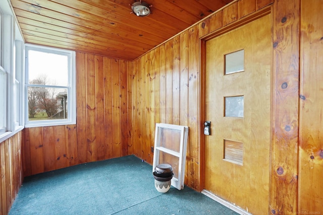 spare room with wooden walls, wood ceiling, and dark carpet