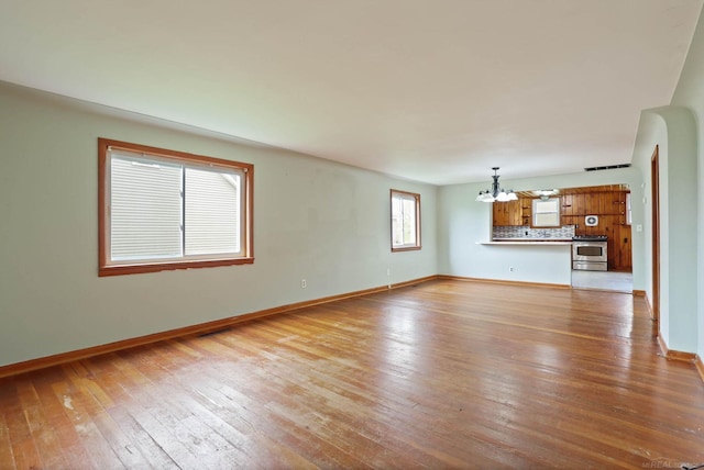 unfurnished living room with light hardwood / wood-style floors and a notable chandelier