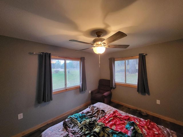 bedroom with multiple windows, dark hardwood / wood-style flooring, and ceiling fan