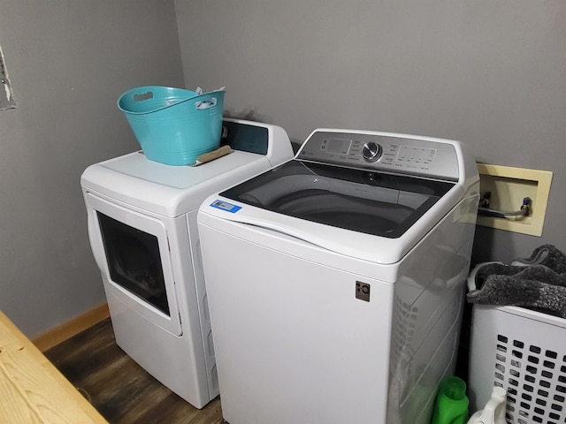 clothes washing area with washer and dryer and dark wood-type flooring