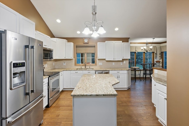 kitchen with a center island, stainless steel appliances, hanging light fixtures, and a notable chandelier