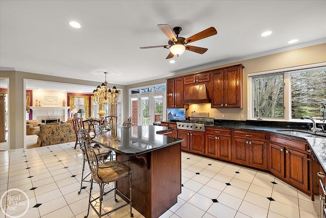 kitchen with ornamental molding, a breakfast bar, premium range hood, a fireplace, and a sink