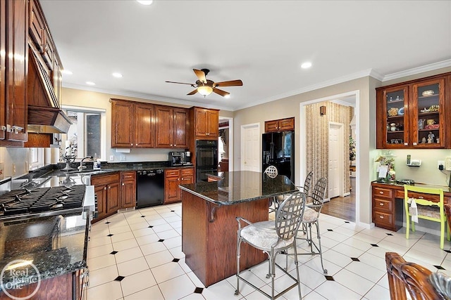 kitchen with a sink, a kitchen island, a ceiling fan, black appliances, and a kitchen bar