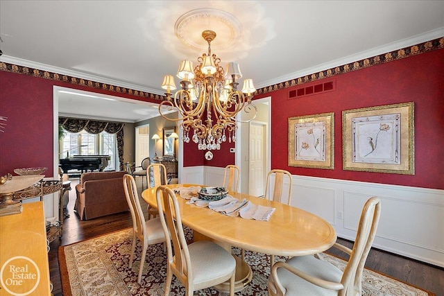 dining area featuring wainscoting, visible vents, crown molding, and wood finished floors