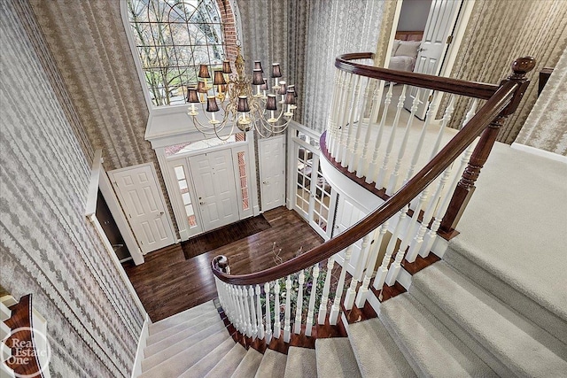 foyer entrance with wallpapered walls, a notable chandelier, and wood finished floors