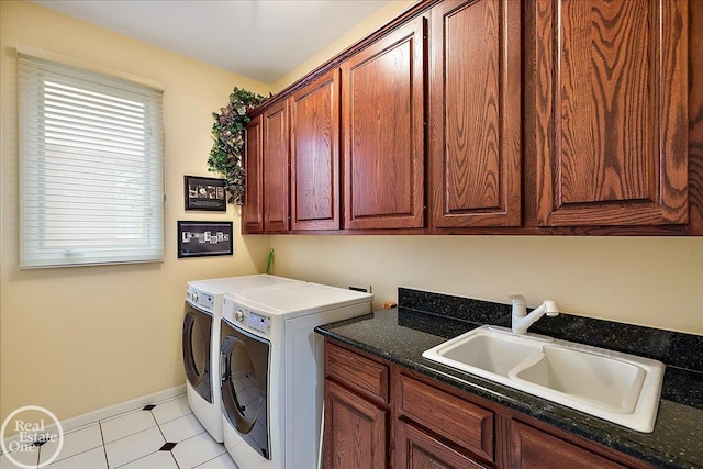 laundry area with light tile patterned floors, separate washer and dryer, a sink, baseboards, and cabinet space