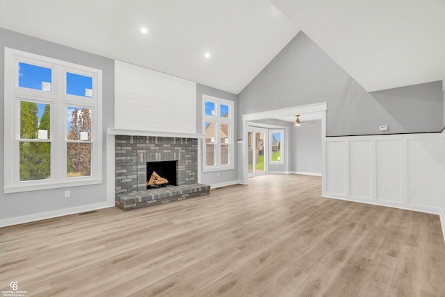 unfurnished living room with light hardwood / wood-style flooring, a brick fireplace, ceiling fan, and a healthy amount of sunlight