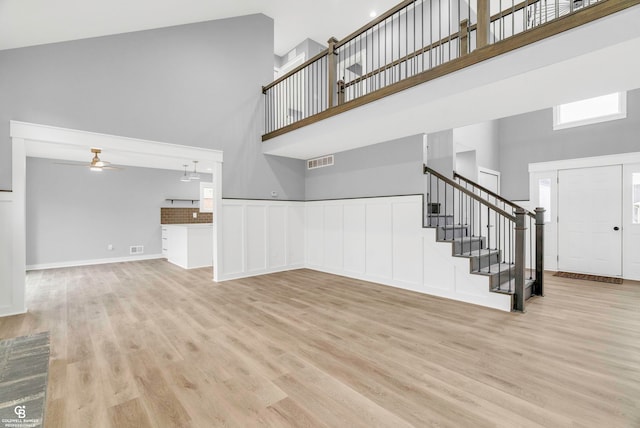 unfurnished living room featuring ceiling fan, high vaulted ceiling, and light wood-type flooring