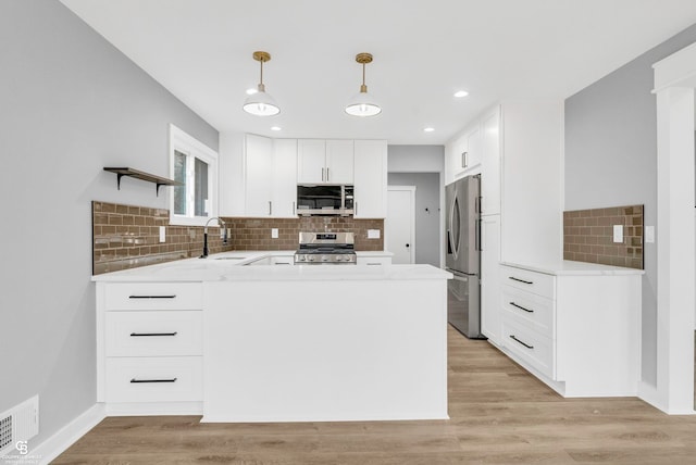 kitchen with white cabinets, sink, appliances with stainless steel finishes, decorative light fixtures, and kitchen peninsula