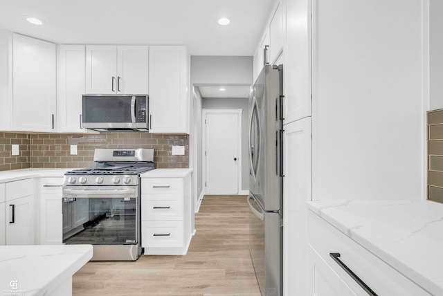 kitchen with appliances with stainless steel finishes, light hardwood / wood-style floors, and white cabinetry