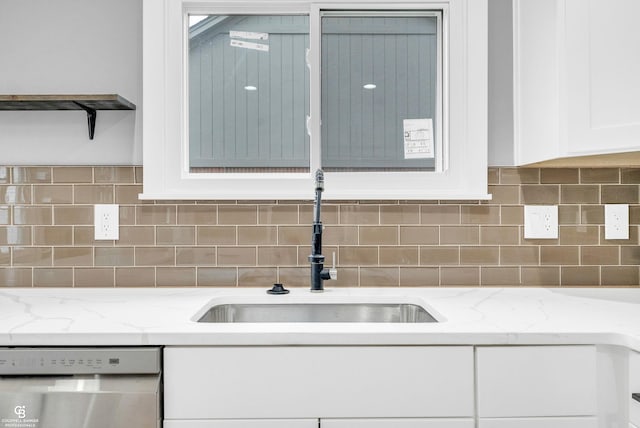 kitchen with backsplash, light stone counters, white cabinets, and stainless steel dishwasher