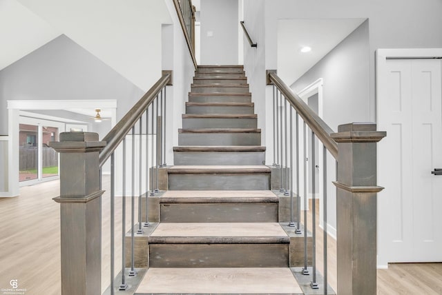 stairway featuring wood-type flooring, a towering ceiling, and french doors