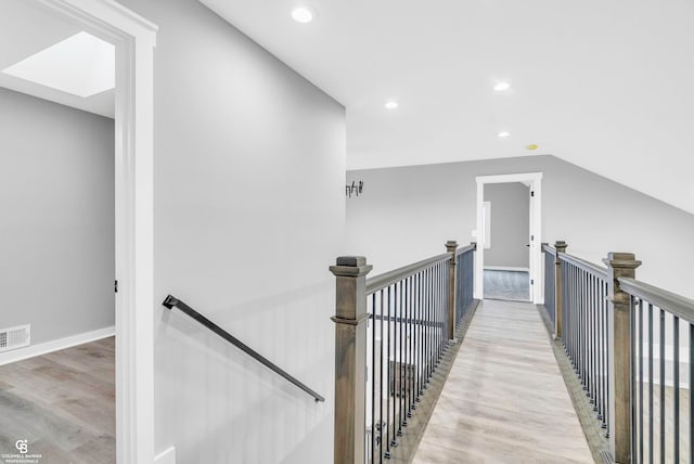 hallway featuring light hardwood / wood-style floors and lofted ceiling with skylight