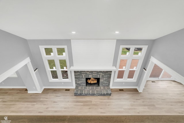 unfurnished living room featuring a fireplace, light hardwood / wood-style flooring, and plenty of natural light