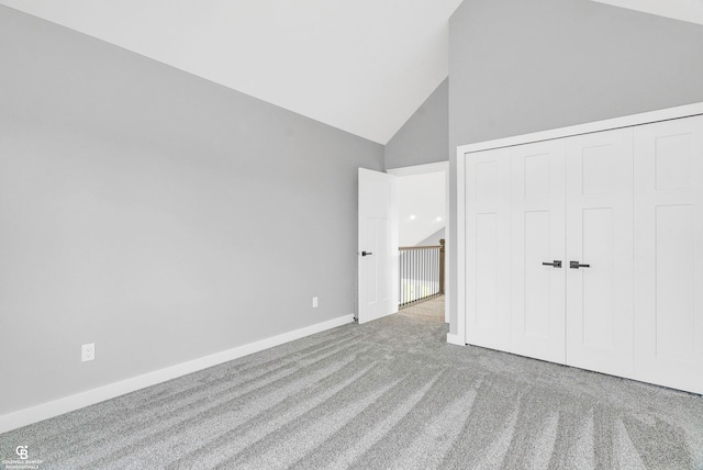 unfurnished bedroom featuring carpet floors, a closet, and high vaulted ceiling