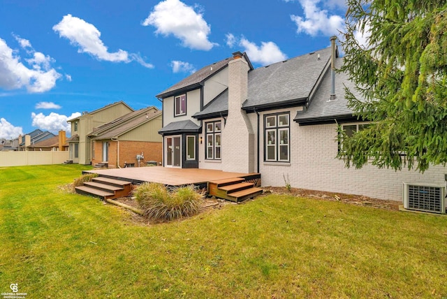 rear view of property featuring cooling unit, a lawn, and a wooden deck