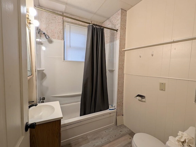 full bathroom with vanity, wooden walls, hardwood / wood-style flooring, toilet, and shower / tub combo with curtain