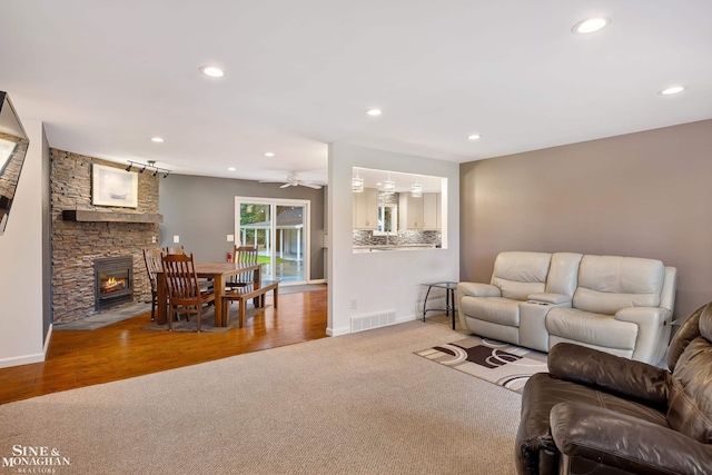 living room featuring a fireplace, hardwood / wood-style floors, and ceiling fan