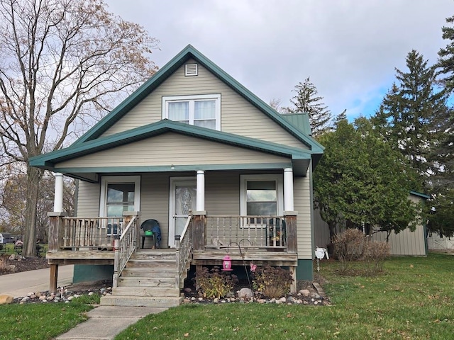 bungalow-style home featuring covered porch and a front yard