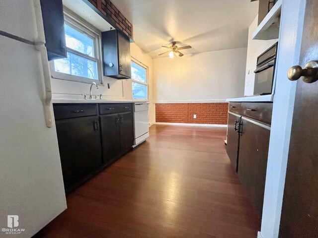 kitchen with dark hardwood / wood-style flooring, brick wall, white appliances, ceiling fan, and sink