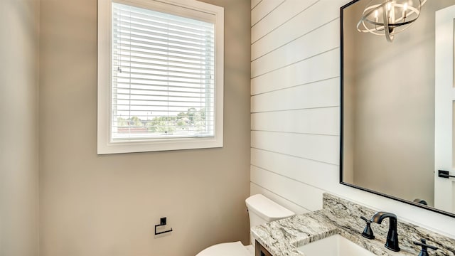 bathroom with wood walls, vanity, and toilet