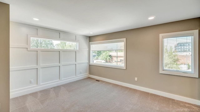 empty room with light carpet, a decorative wall, recessed lighting, and baseboards