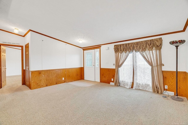 unfurnished room with a textured ceiling, wood walls, ornamental molding, and light carpet