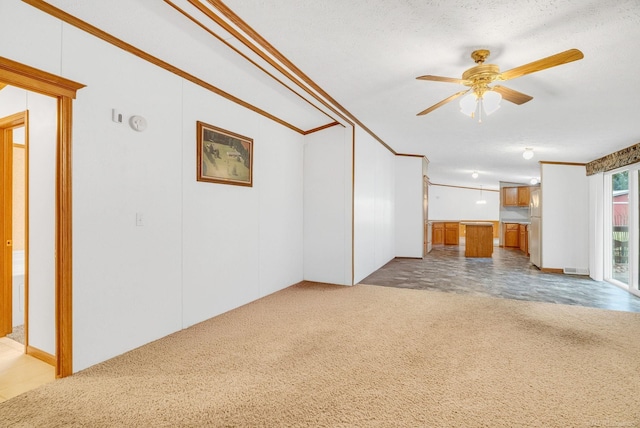 unfurnished living room featuring ceiling fan, crown molding, light colored carpet, and a textured ceiling