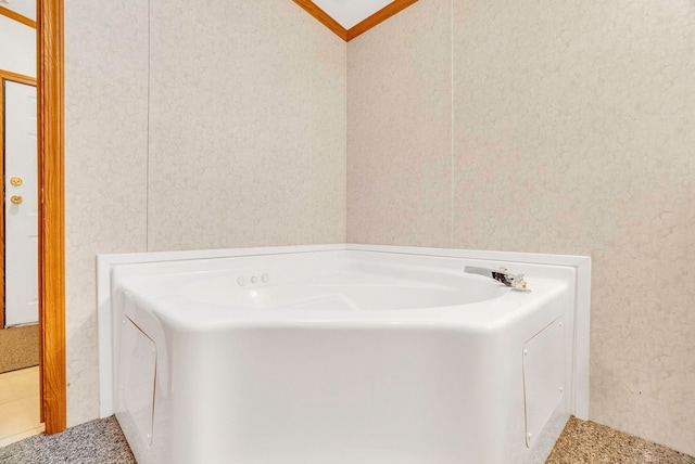 bathroom with ornamental molding and a tub