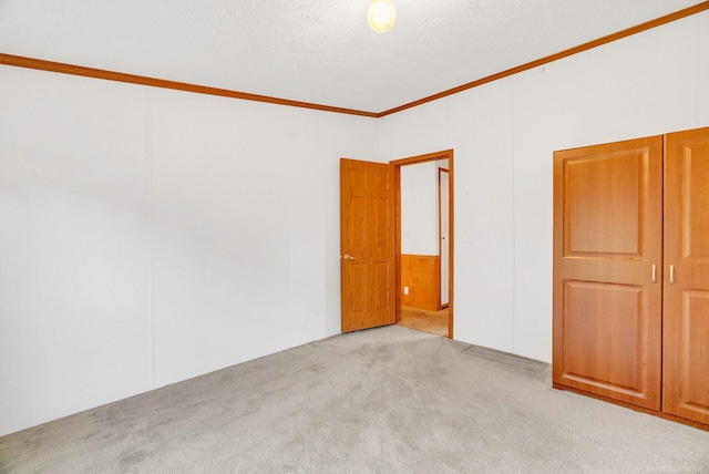 carpeted empty room featuring a textured ceiling and ornamental molding